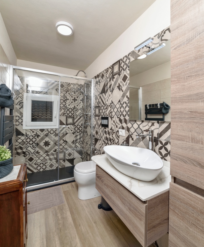 Salle de bain rénovée avec douche vitrée, meuble vasque suspendu et carrelage décoratif